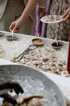 two people are serving oysters at an outdoor event