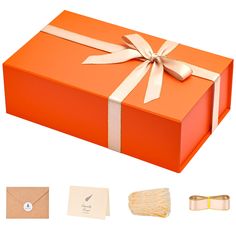 an orange gift box with white ribbon and two matching napkins next to each other