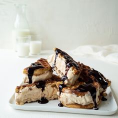 some waffles with ice cream and chocolate drizzled on them sitting on a white plate