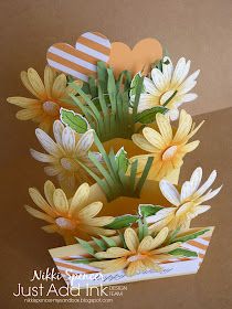 a card with yellow flowers and hearts on it's side, sitting on a table