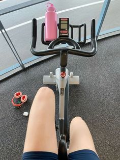 a person riding a stationary bike with a pink water bottle on the handlebars