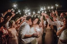 a bride and groom are surrounded by their guests holding sparklers