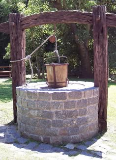 an old fashioned bucket is on top of a brick wall in the middle of a park