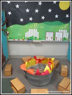 a bucket filled with construction paper sitting on top of a floor next to wooden blocks