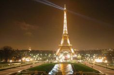 the eiffel tower lit up at night with lights on it's sides