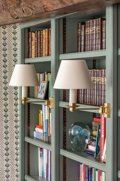 two lamps are sitting on the bookshelves in front of some shelves filled with books