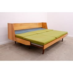 a bed that is sitting in the middle of some concrete flooring with a green mattress on it