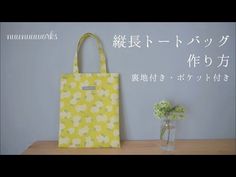 a yellow bag sitting on top of a table next to a vase with flowers in it