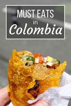 someone holding up a piece of food with the words must eats in colombia