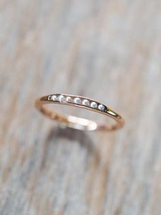 a close up of a gold ring on a wooden surface with white pearls in the middle