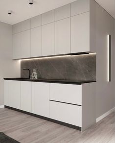 an empty kitchen with white cabinets and black counter tops on the wall, along with wooden flooring