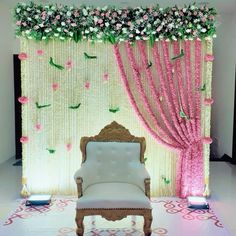 a white chair sitting in front of a wall with flowers and greenery on it