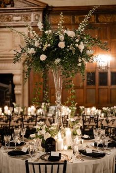 a table set up for a formal dinner with candles and centerpieces in the middle