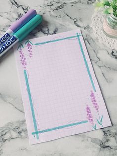 a piece of paper sitting on top of a table next to two markers and a potted plant