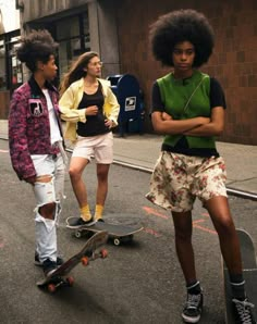 three young people are standing on skateboards in the middle of an urban street,