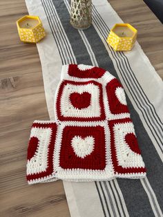 a red and white crocheted blanket sitting on top of a striped table cloth