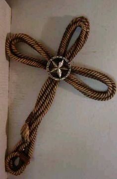 a cross made out of rope on top of a white surface with a metal ring