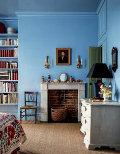 a bedroom with blue walls and a fireplace in the corner, surrounded by bookshelves