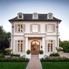 a large white house with two story windows and an entry way leading to the front door