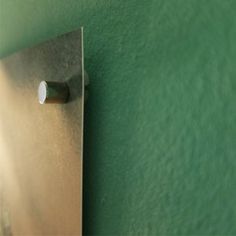 a metal object mounted to the side of a green wall