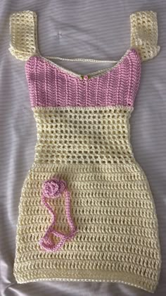 a crocheted baby's dress is laying on a bed