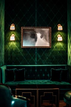 a living room with green velvet couches and two lamps on either side of the wall