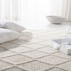 a white rug with some pillows on it and a bowl in the corner next to it