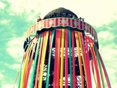 an amusement park ride with colorful streamers on it's sides and sky in the background