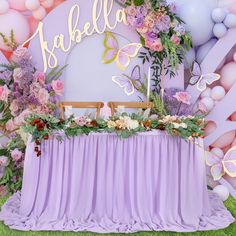 the table is set up for a party with balloons, flowers and butterflies on it