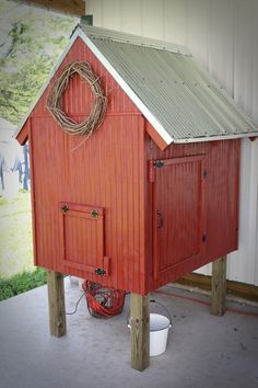 a red shed with a wreath on the roof and a hose attached to it's side