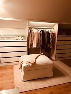 a white bed sitting in a bedroom next to a closet filled with drawers and clothes