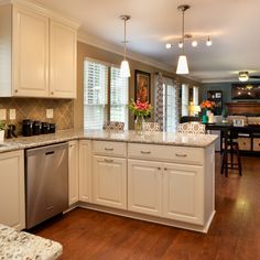 a kitchen with white cabinets and marble counter tops