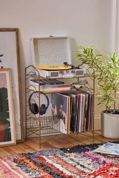 a record player sits on top of a metal rack next to a potted plant