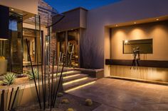 a modern home at night with lights on the front door and stairs leading up to it