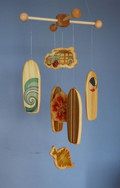 a mobile with surfboards and cars hanging from it's sides on a blue wall