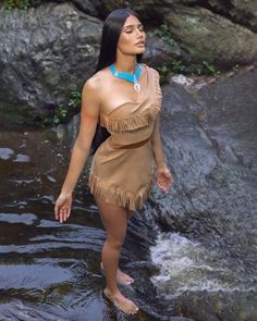 a woman standing in the water wearing a native style dress and holding her hand out