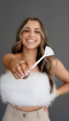 a woman holding a white toothbrush in her right hand and smiling at the camera