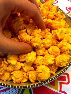 a person is picking up popcorn from a bowl