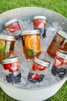 six mason jars filled with different types of fruit jams in ice on the grass