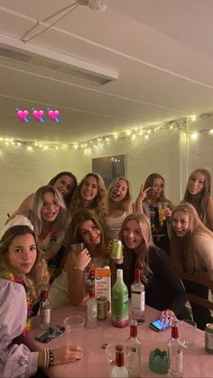 a group of women sitting at a table posing for the camera with drinks in front of them