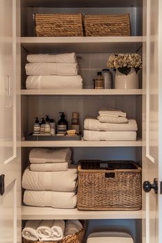 an organized linen closet with baskets and towels