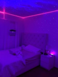 a bed in a room with purple lights on the ceiling