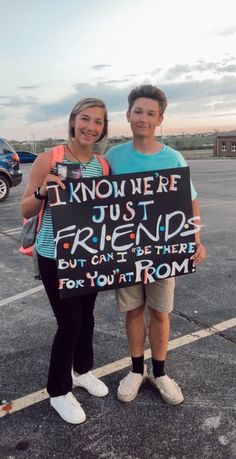 two people standing in a parking lot holding a sign