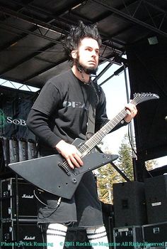 a man standing on stage with a guitar in his hand and holding it up to the camera