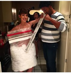 a woman in a white dress is wrapped in plastic and posing for the camera with a man