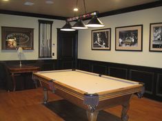 a pool table in a room with pictures on the wall