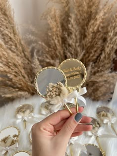 a person holding two lollipops in front of some dried grass and flowers