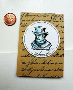 a penny sitting on top of a piece of paper next to a card with an image of a man wearing a hat