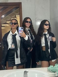 three women in black and white outfits are taking a selfie with their cell phones