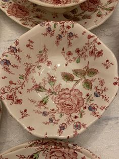 three plates with floral designs on them sitting on a table